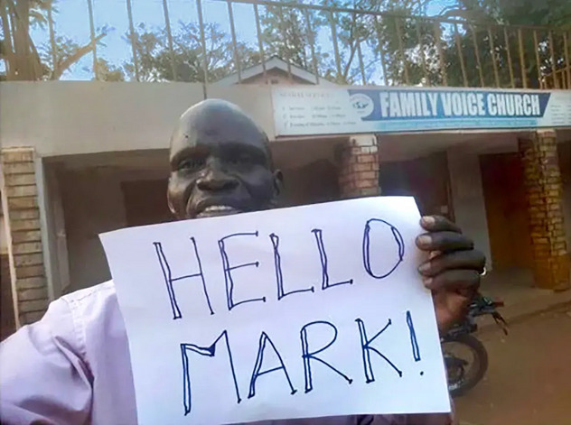 Pastor Musa holding Hello Mark sign